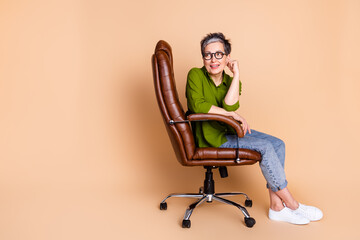 Canvas Print - Photo portrait of lovely pensioner lady look empty space sit armchair dressed stylish green garment isolated on beige color background