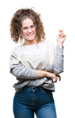 Sticker - Beautiful brunette curly hair young girl wearing glasses over isolated background with a big smile on face, pointing with hand and finger to the side looking at the camera.