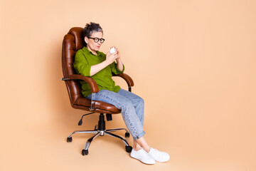 Poster - Full body photo of attractive retired woman sit armchair stress crumpled paper dressed green clothes isolated on beige color background