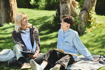 Wall Mural - Two queer friends, dressed casually, sit on a blanket in a park on a sunny day.