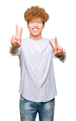 Wall Mural - Young handsome business man with afro hair wearing elegant shirt smiling looking to the camera showing fingers doing victory sign. Number two.