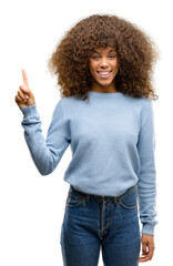 Sticker - African american woman wearing a sweater showing and pointing up with finger number one while smiling confident and happy.