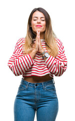 Poster - Young beautiful woman casual stripes winter sweater over isolated background praying with hands together asking for forgiveness smiling confident.