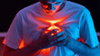 © pavelkant - Conceptual photography. The man covers the bright red light coming from his chest with his hands. Mental pain or a broken heart