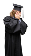 Canvas Print - Young handsome graduated man with long hair over isolated background with sad expression covering face with hands while crying. Depression concept.