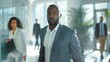 © venusvi - Determined black businessman walking towards male and female colleagues in a bright office space