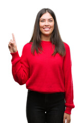 Wall Mural - Young beautiful hispanic wearing red sweater showing and pointing up with finger number one while smiling confident and happy.