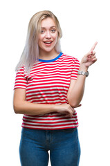 Wall Mural - Young blonde woman over isolated background with a big smile on face, pointing with hand and finger to the side looking at the camera.