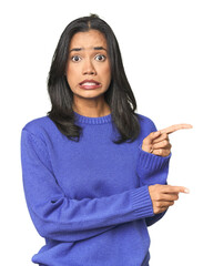 simple portrait of a young latina shocked pointing with index fingers to a copy space.
