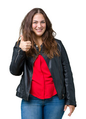 Wall Mural - Beautiful plus size young woman wearing a fashion leather jacket over isolated background doing happy thumbs up gesture with hand. Approving expression looking at the camera showing success.