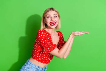 Sticker - Photo of cheerful glad lovely cute woman wear red trendy clothes hold brand empty space isolated on green color background