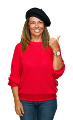 Wall Mural - Middle age adult woman wearing fashion beret over isolated background doing happy thumbs up gesture with hand. Approving expression looking at the camera with showing success.