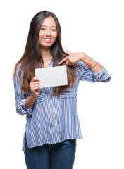 Sticker - Young asian woman holding blank card over isolated background with surprise face pointing finger to himself