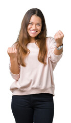 Wall Mural - Young beautiful brunette woman wearing pink sweatshirt over isolated background very happy and excited doing winner gesture with arms raised, smiling and screaming for success. Celebration concept.