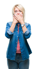 Poster - Young beautiful blonde woman wearing denim jacket over isolated background shocked covering mouth with hands for mistake. Secret concept.