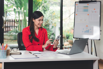 Woman hold smartphone while working in coworking space coffee shop. Young business woman sitting in office at desk and using smartphone. Business woman working at the desk and using a smartphone.