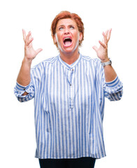 Poster - Atrractive senior caucasian redhead woman over isolated background crazy and mad shouting and yelling with aggressive expression and arms raised. Frustration concept.