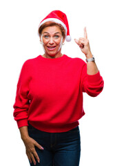 Poster - Atrractive senior caucasian redhead woman wearing christmas hat over isolated background pointing finger up with successful idea. Exited and happy. Number one.