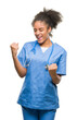 © Krakenimages.com - Young afro american doctor woman over isolated background very happy and excited doing winner gesture with arms raised, smiling and screaming for success. Celebration concept.
