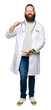 © Krakenimages.com - Young blond doctor man with beard wearing medical coat gesturing with hands showing big and large size sign, measure symbol. Smiling looking at the camera. Measuring concept.