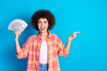 Canvas Print - Photo portrait of lovely young lady hold money fan point empty space dressed stylish checkered garment isolated on blue color background