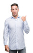 © Krakenimages.com - Handsome young businessman smiling with happy face looking and pointing to the side with thumb up.