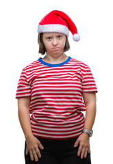 Wall Mural - Young adult woman with down syndrome wearing christmas hat over isolated background with serious expression on face. Simple and natural looking at the camera.