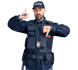 Wall Mural - Young handsome man wearing police uniform doing thumbs up and down, disagreement and agreement expression. crazy conflict