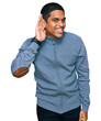 © Krakenimages.com - Young handsome hispanic man wearing casual sweatshirt smiling with hand over ear listening an hearing to rumor or gossip. deafness concept.