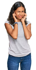 Wall Mural - Young african american girl wearing casual clothes covering ears with fingers with annoyed expression for the noise of loud music. deaf concept.