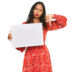 Canvas Print - Young african american girl holding blank empty banner with angry face, negative sign showing dislike with thumbs down, rejection concept