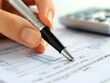 © sukrit - Macro shot of a person's hand holding a pen and checking a financial report