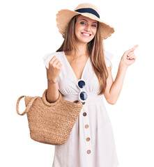 Wall Mural - Young beautiful blonde woman wearing summer dress and wicker handbag smiling happy pointing with hand and finger to the side