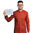 © Krakenimages.com - Young hispanic man with beard holding travel calendar looking positive and happy standing and smiling with a confident smile showing teeth