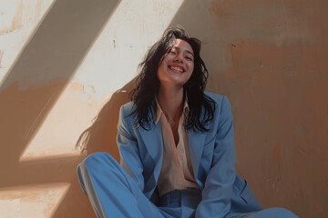 Wall Mural - A woman is sitting on the floor wearing a blue suit and smiling. Scene is happy and relaxed