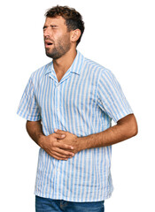 Canvas Print - Handsome young man with beard wearing casual fresh shirt with hand on stomach because nausea, painful disease feeling unwell. ache concept.