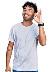 Poster - Hispanic young man with beard wearing casual white t shirt smiling positive doing ok sign with hand and fingers. successful expression.