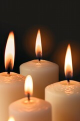 Wall Mural - A close up of four candles with their flames visible. The candles are lit and the image conveys a sense of warmth and comfort