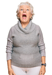 Wall Mural - Senior grey-haired woman wearing casual winter sweater angry and mad screaming frustrated and furious, shouting with anger. rage and aggressive concept.