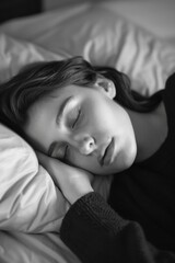 Wall Mural - A woman is sleeping on a bed with a pillow. She is wearing a black sweater. The image has a mood of relaxation and peacefulness