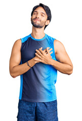 Canvas Print - Handsome hispanic man wearing sportswear smiling with hands on chest with closed eyes and grateful gesture on face. health concept.