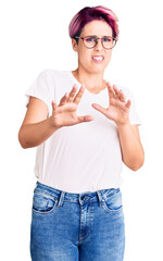 Canvas Print - Young beautiful woman with pink hair wearing casual clothes and glasses disgusted expression, displeased and fearful doing disgust face because aversion reaction. with hands raised