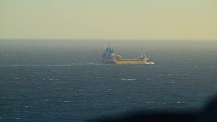 Wall Mural - Cargo ship voyaging westward in windy weather