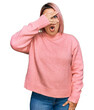 © Krakenimages.com - Hispanic woman with pink hair wearing casual winter sweater peeking in shock covering face and eyes with hand, looking through fingers with embarrassed expression.