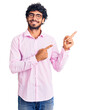 © Krakenimages.com - Handsome young man with curly hair and bear wearing business clothes smiling and looking at the camera pointing with two hands and fingers to the side.