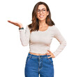 © Krakenimages.com - Young brunette woman wearing casual clothes and glasses smiling cheerful presenting and pointing with palm of hand looking at the camera.