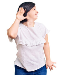 Poster - Brunette woman with down syndrome wearing casual white tshirt smiling with hand over ear listening an hearing to rumor or gossip. deafness concept.