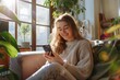 © Athena  - happy young female sitting on a sofa scrolling on her phone at home