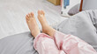 © Krakenimages.com - Close-up of bare feet in bed with pink pajamas showcasing relaxation in a cozy bedroom setting.