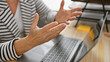 © Krakenimages.com - A close-up of a middle-aged woman explaining something in an office, her hands gesturing with a laptop blurred in the foreground.